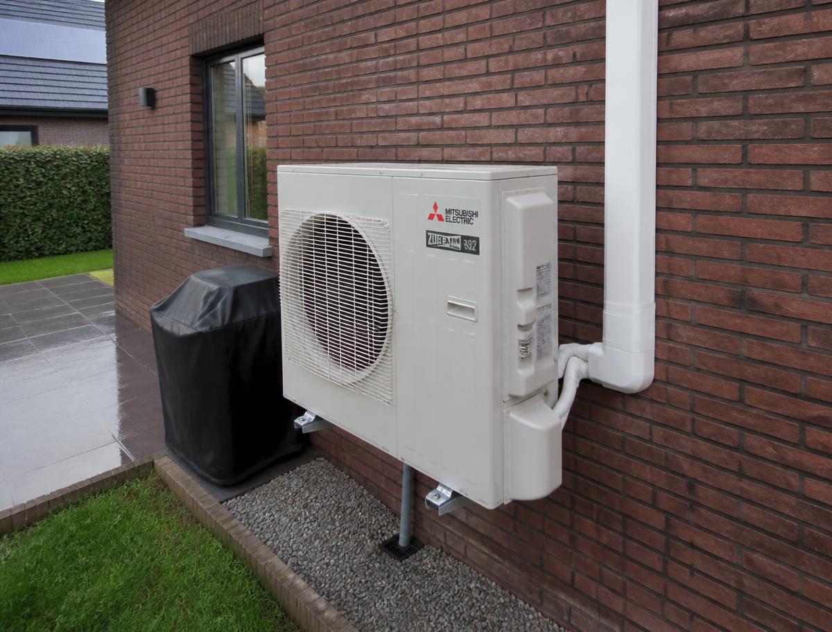 Buitenunit met verzorgd leidingwerk tegen een bakstenen gevel